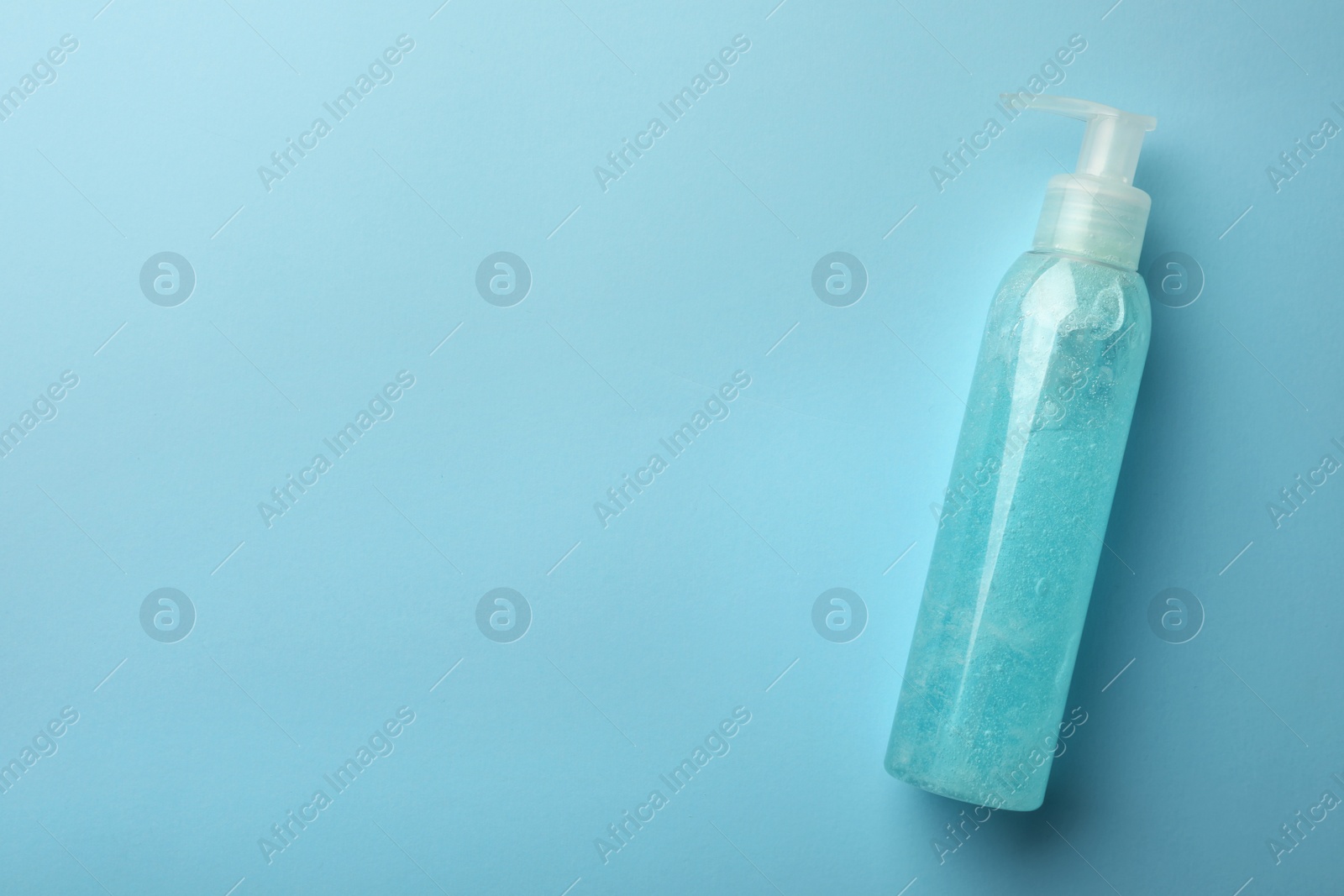 Photo of Bottle of cosmetic gel on light blue background, top view. Space for text