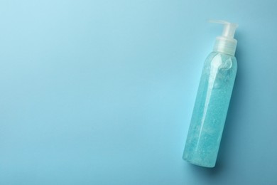 Bottle of cosmetic gel on light blue background, top view. Space for text