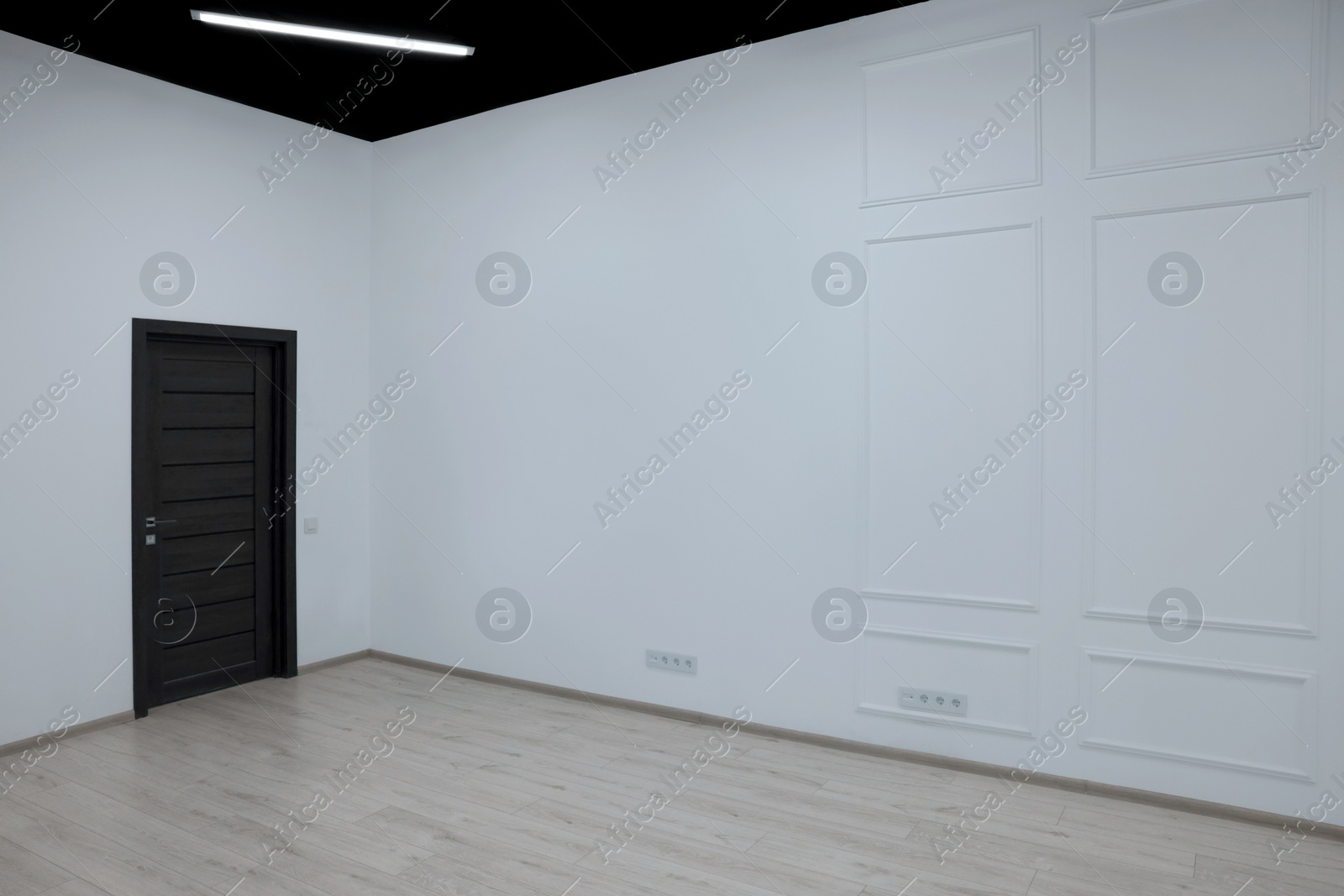 Photo of Empty renovated room with white walls and black door