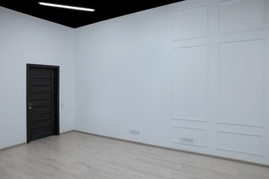 Empty renovated room with white walls and black door