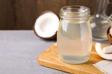 Photo of Coconut oil on grey wooden table. Space for text