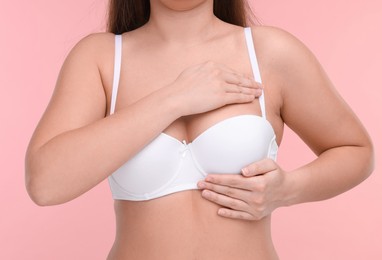 Mammology. Woman in bra doing breast self-examination on pink background, closeup