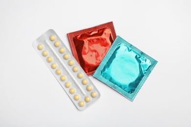 Photo of Condoms and birth control pills on light grey background, flat lay. Safe sex concept