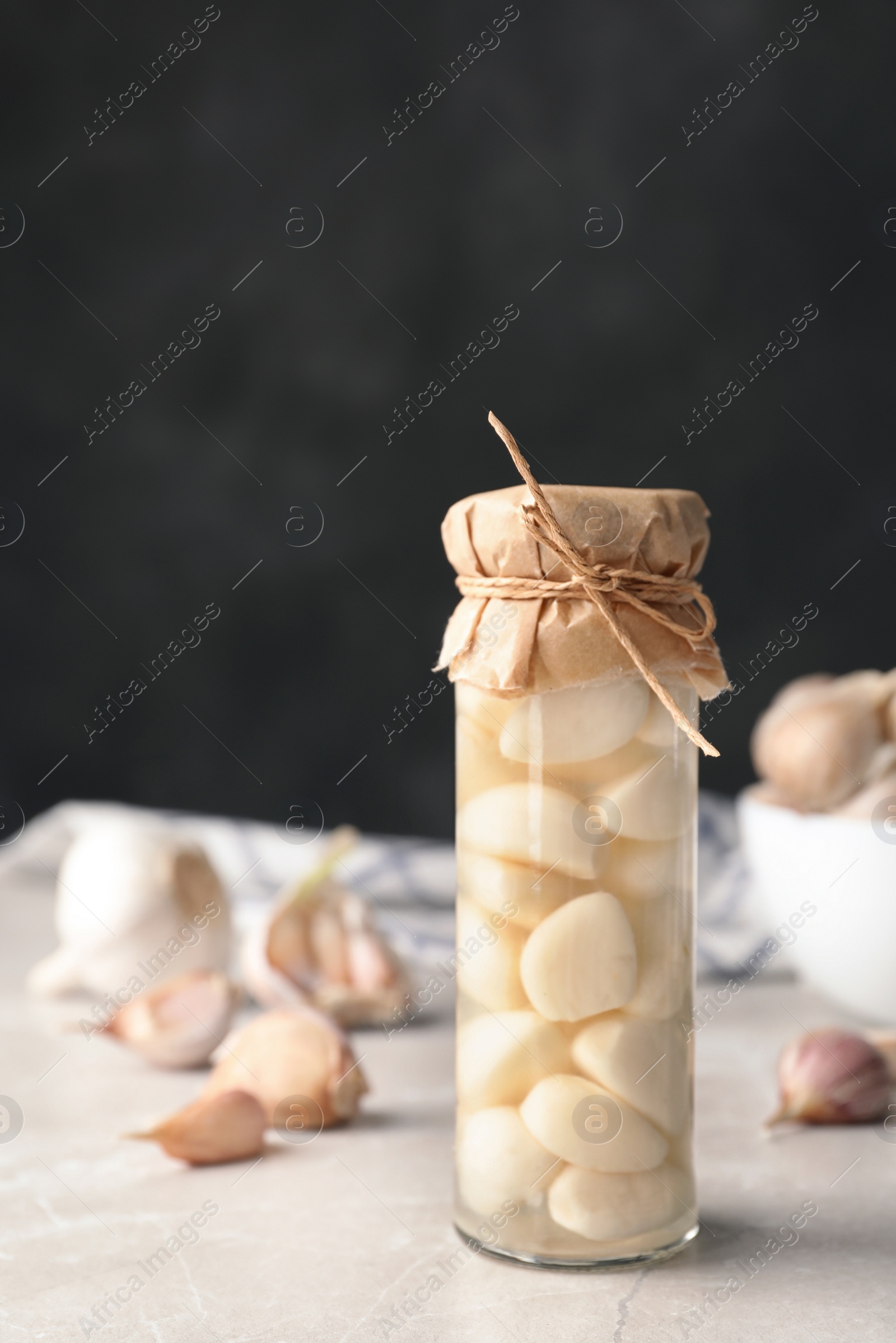 Photo of Preserved garlic in glass jar on table. Space for text