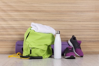 Photo of Backpack and sports equipment on floor indoors