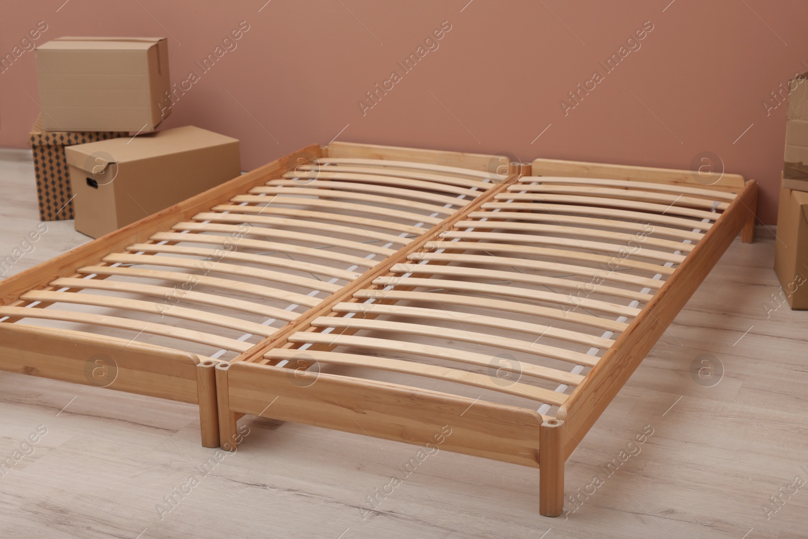 Photo of Wooden bed frame and cardboard boxes on floor in room