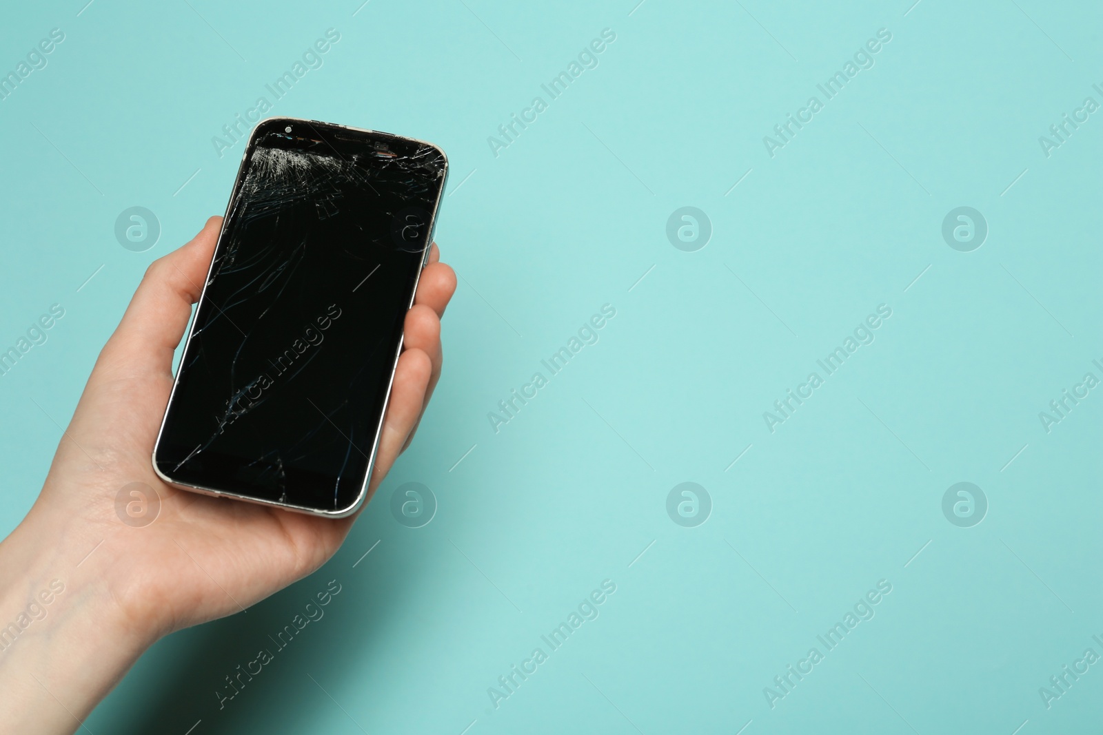 Photo of Woman holding damaged smartphone on light blue background, closeup with space for text. Device repairing