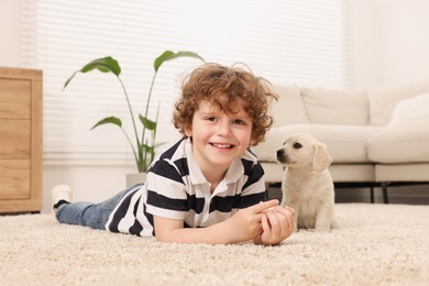 Photo of Little boy with cute puppy on beige carpet indoors