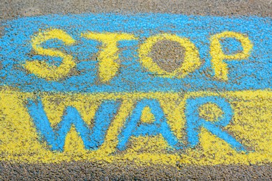 Photo of Ukrainian flag with words Stop War drawn with colorful chalks on asphalt outdoors, closeup