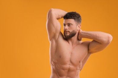 Photo of Muscular man on orange background, space for text. Sexy body