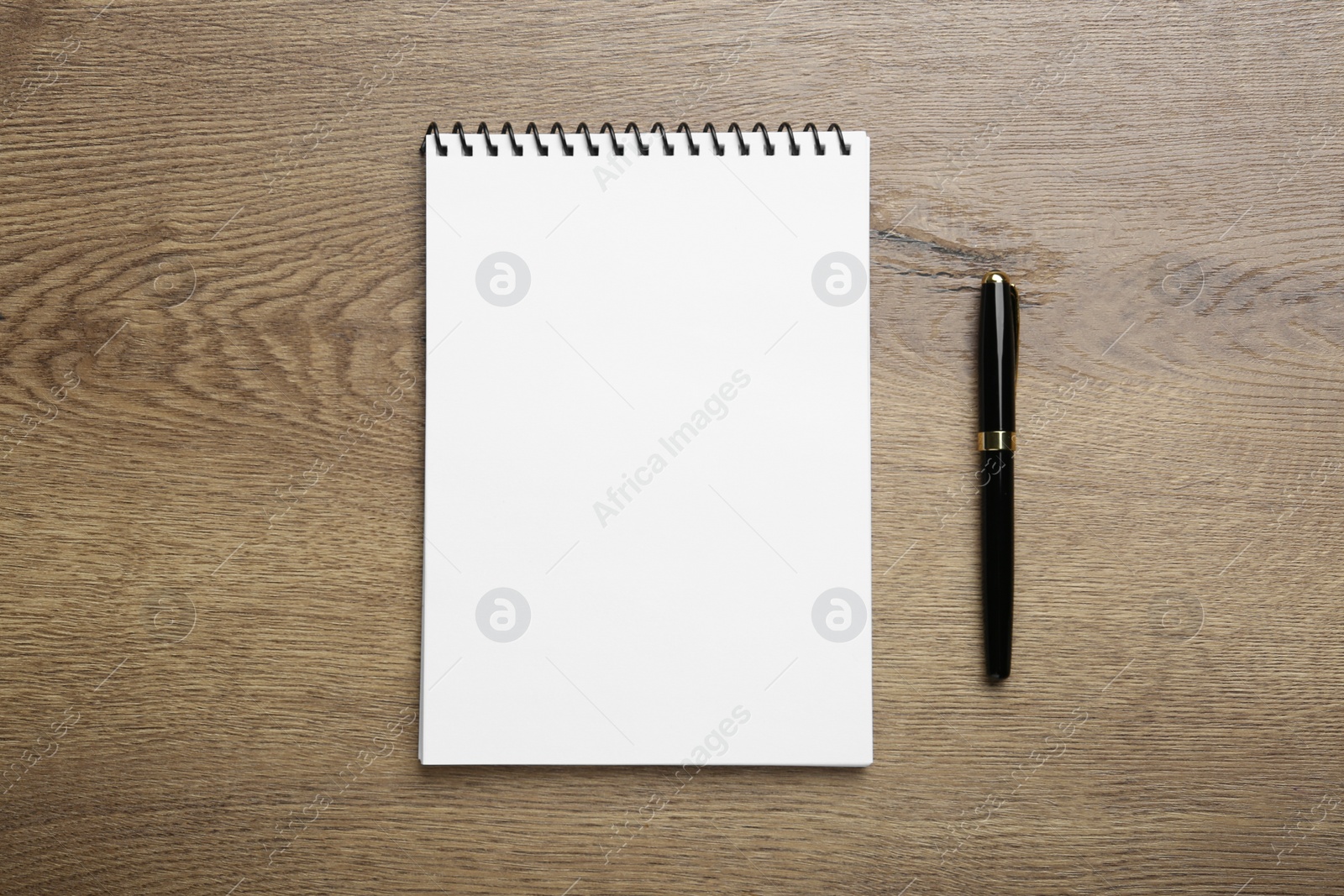 Photo of Notebook and pen on wooden table, top view