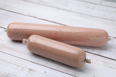 Photo of Delicious liver sausages on white wooden table