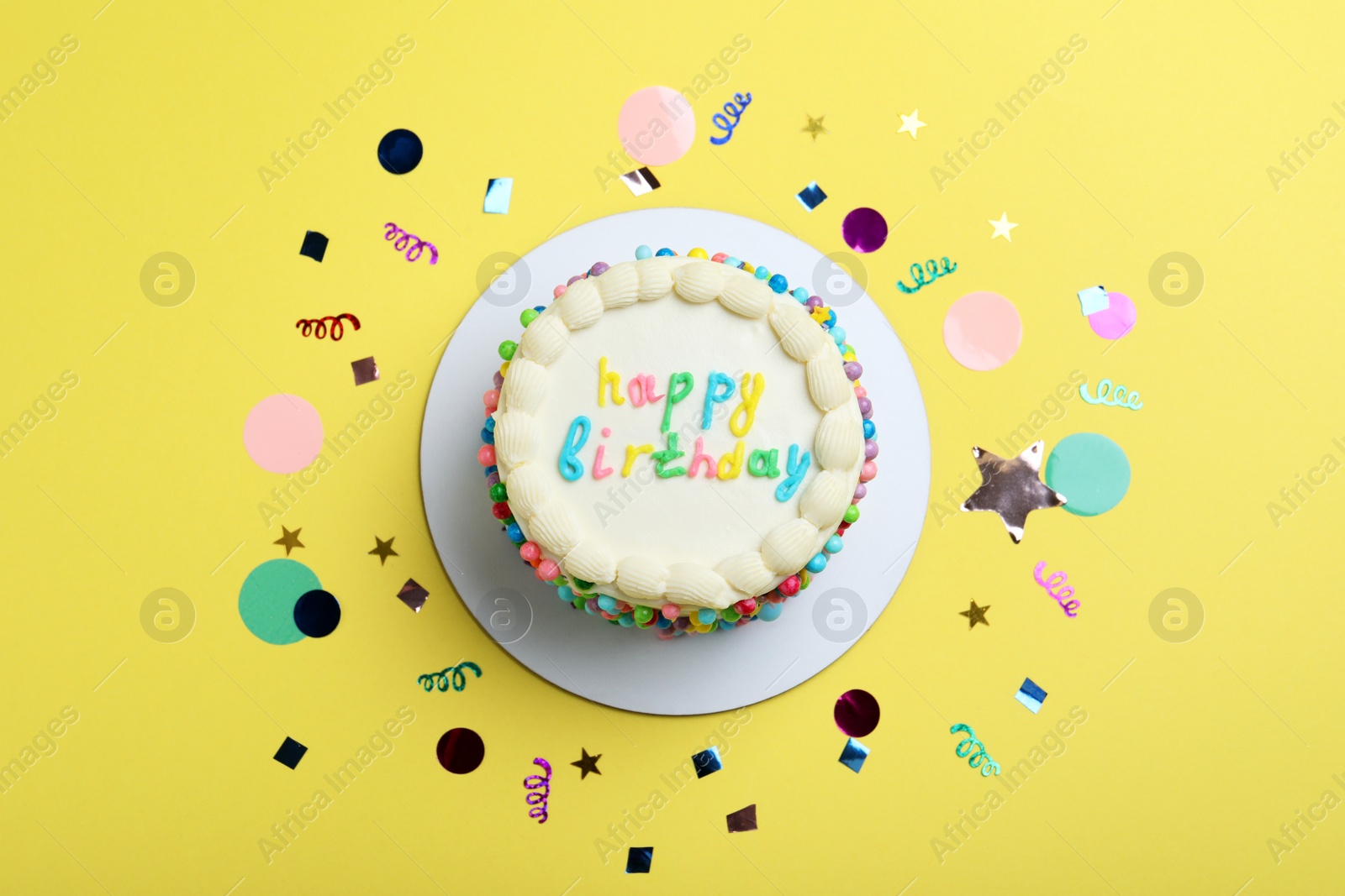 Photo of Cute bento cake with tasty cream and confetti on yellow background, flat lay