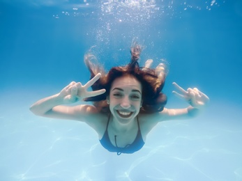 Photo of Beautiful young woman swimming in pool, underwater view