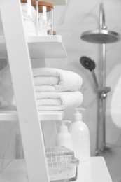 Photo of Stacked bath towels on white shelf in bathroom