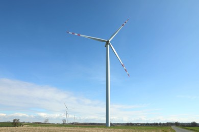 Modern wind turbines in field on sunny day. Alternative energy source