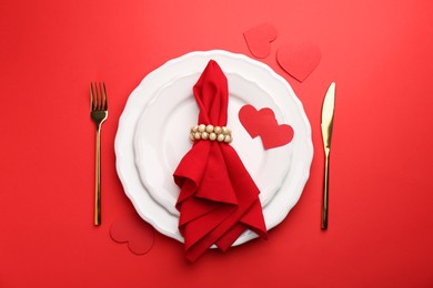 Photo of Place setting with paper hearts on red table, top view. Romantic dinner