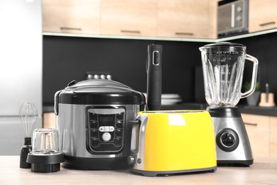 Modern domestic appliances on wooden table in kitchen