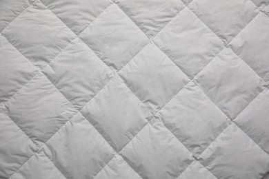 Photo of Soft quilted blanket as background, top view