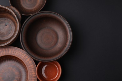 Bowls and plates on black background, flat lay. Space for text