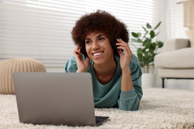 Photo of Beautiful young woman in headphones using laptop in room