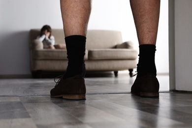 Photo of Adult man without pants standing in front of scared little girl indoors. Child in danger