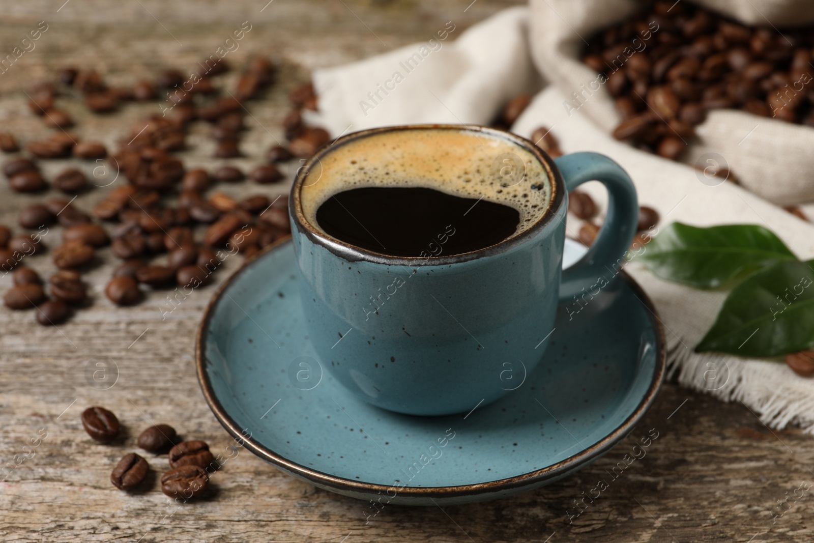 Photo of Cup of aromatic hot coffee and beans on wooden table