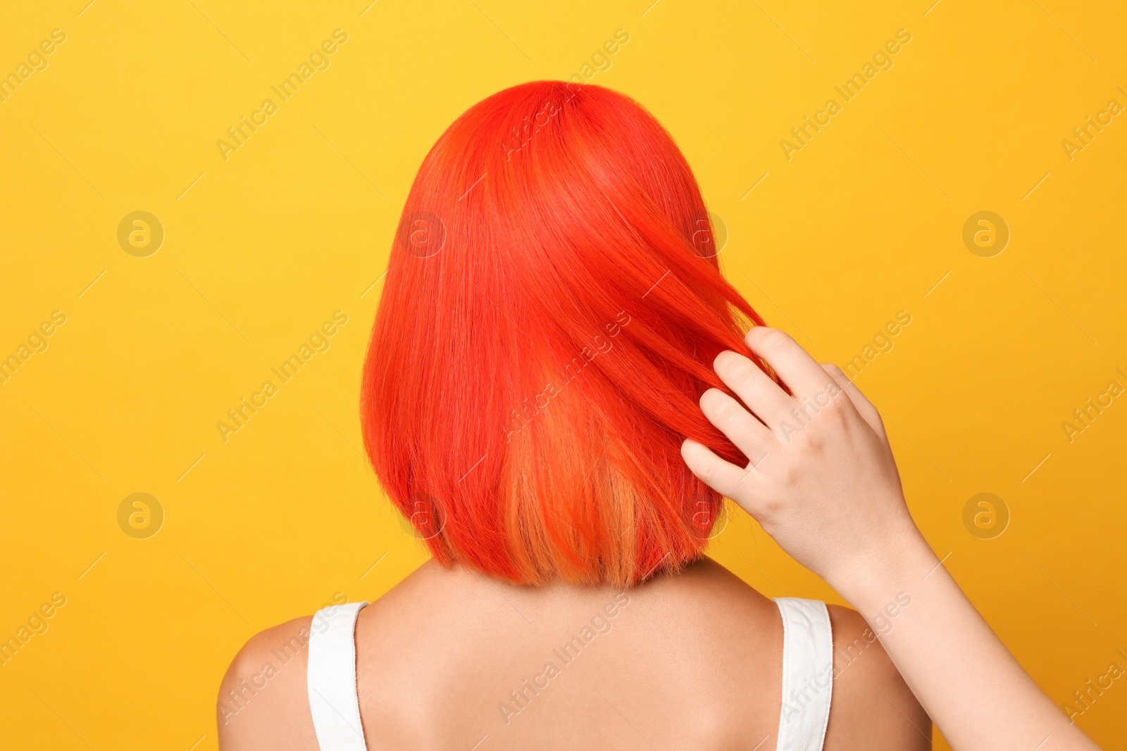 Photo of Professional stylist and young woman with bright dyed hair on orange background, back view