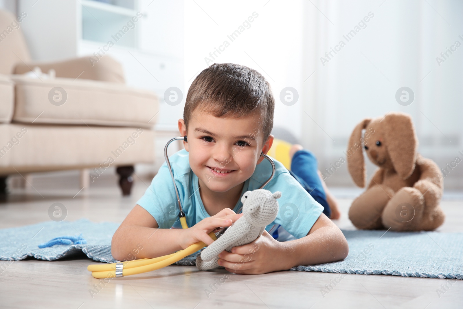 Photo of Cute child imagining himself as doctor while playing with stethoscope and toy at home