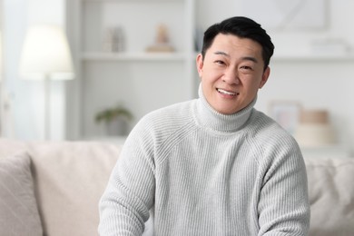 Portrait of smiling man on sofa indoors. Space for text