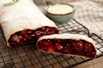 Delicious strudel with cherries on wooden table, closeup