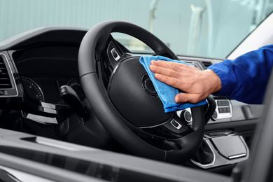 Photo of Car wash worker cleaning automobile interior, closeup