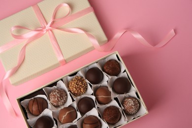 Photo of Box of delicious chocolate candies on pink background, flat lay
