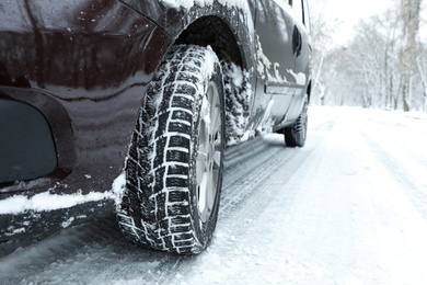 Photo of Modern car with winter tires on snowy road, closeup