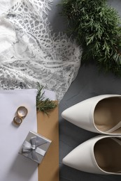 Flat lay composition with wedding dress, white high heel shoes and rings on grey background