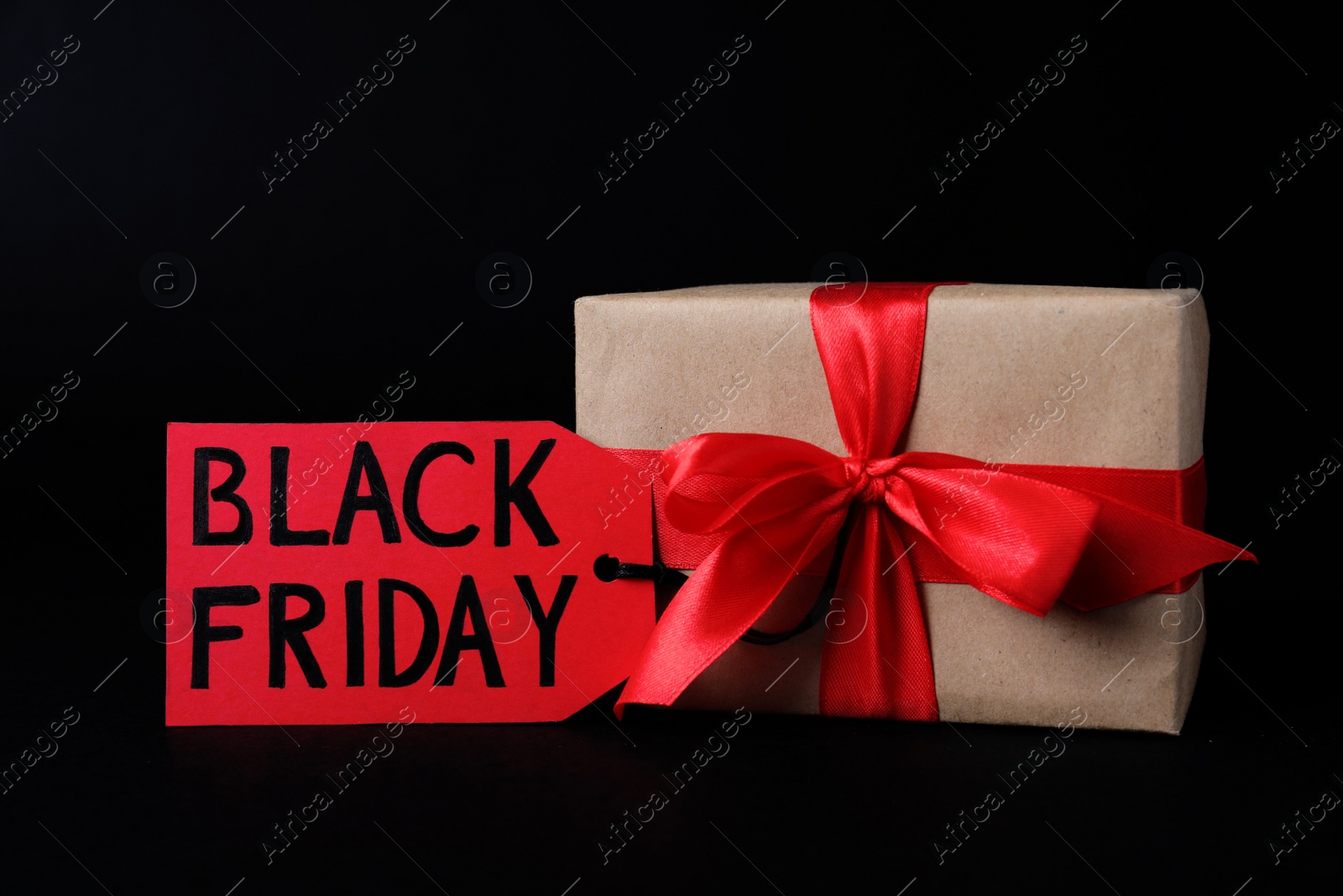 Photo of Gift box and tag with words Black Friday on dark background