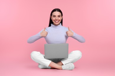 Photo of Happy woman with laptop showing thumbs up on pink background