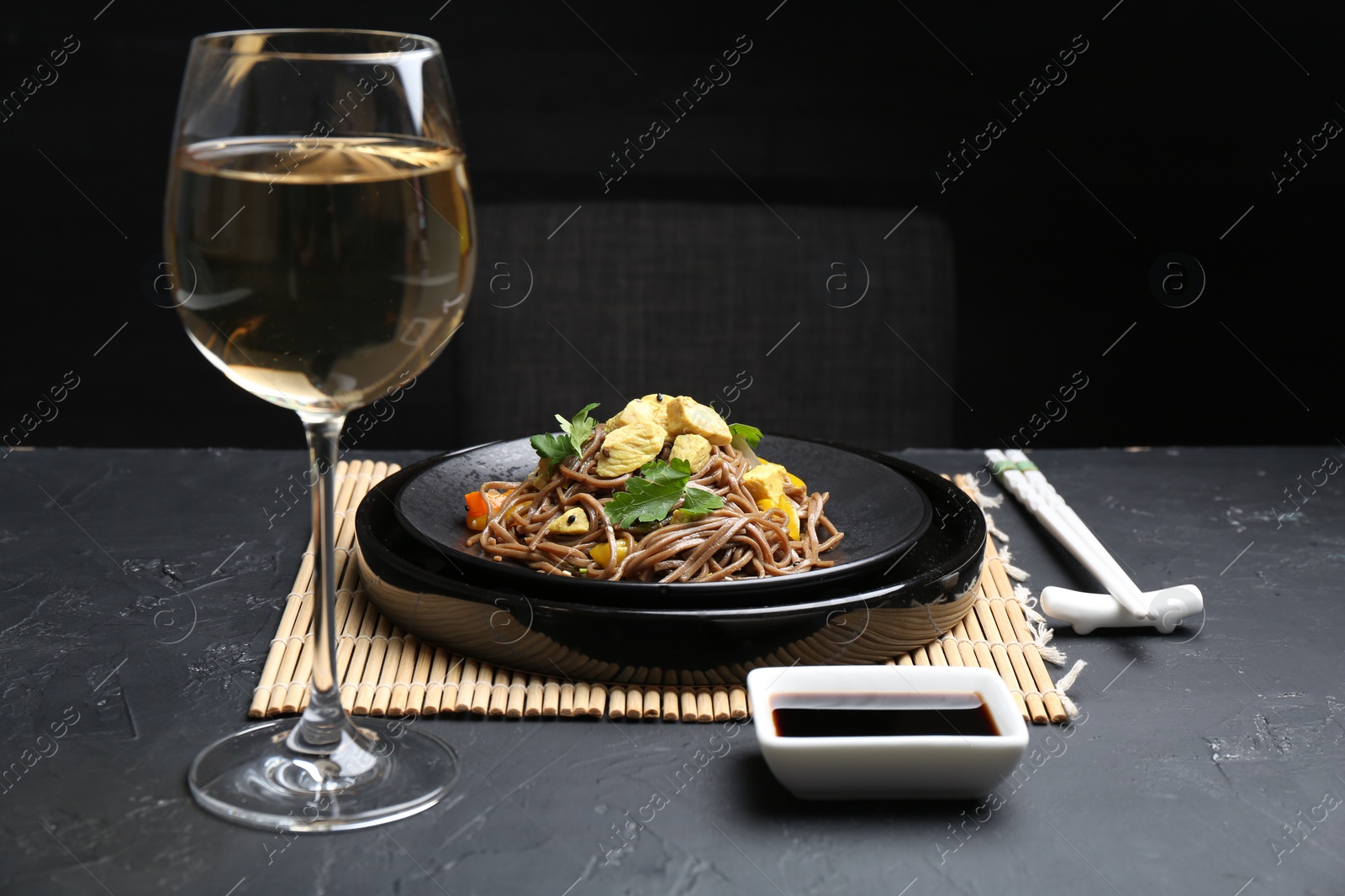 Photo of Stir-fry. Tasty noodles with meat and vegetables served on dark textured table