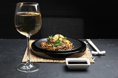 Photo of Stir-fry. Tasty noodles with meat and vegetables served on dark textured table