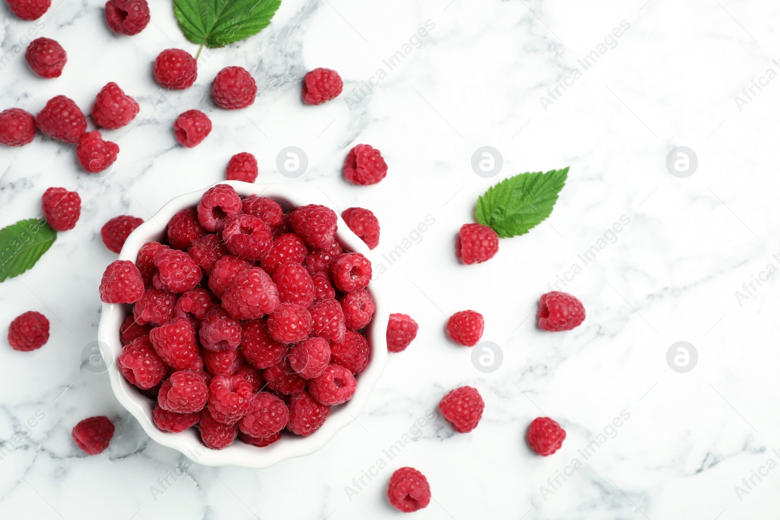 Photo of Bowl with ripe aromatic raspberries on table, top view