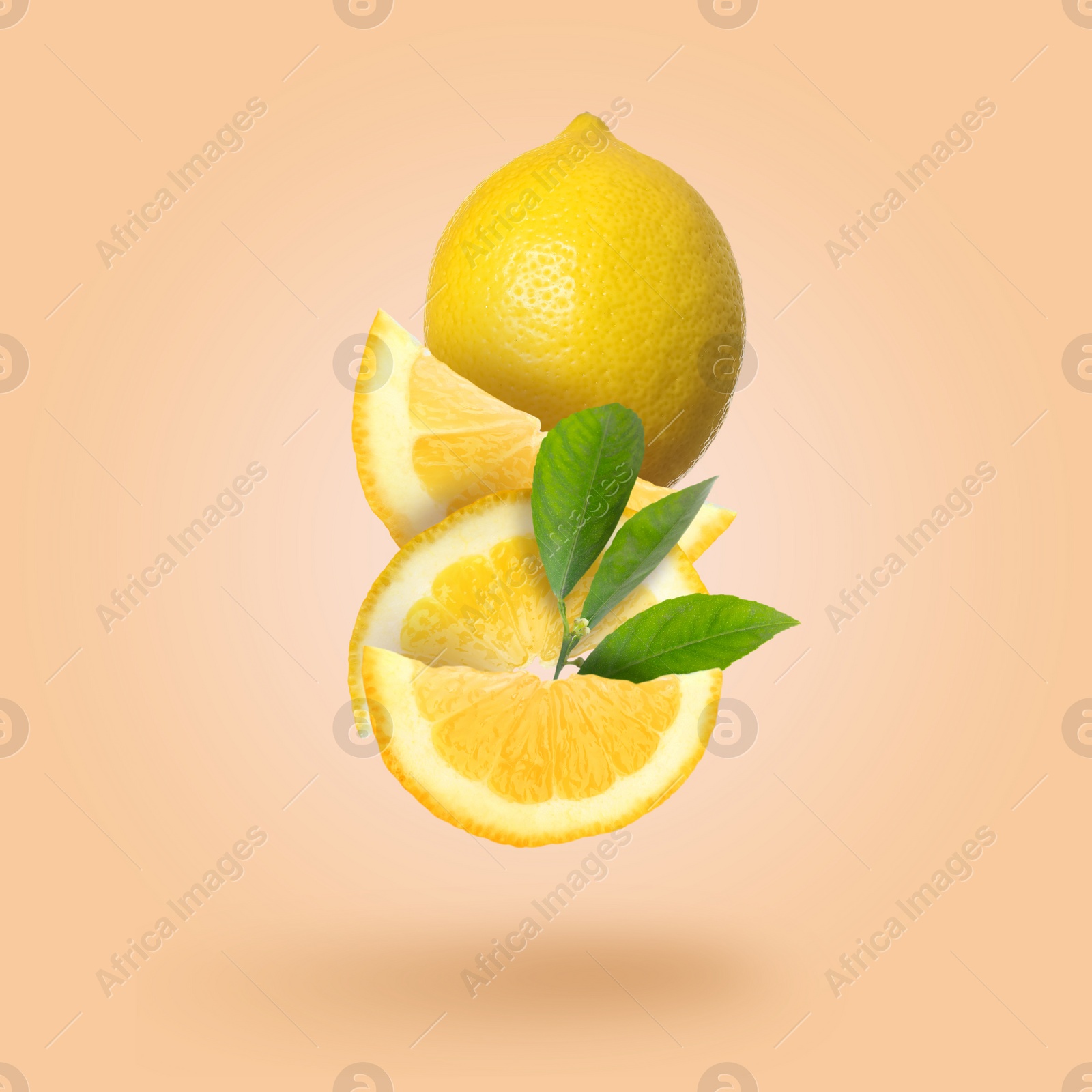 Image of Cut and whole fresh lemons with green leaves falling on pale coral background