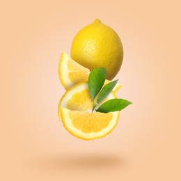 Cut and whole fresh lemons with green leaves falling on pale coral background