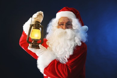 Photo of Merry Christmas. Santa Claus with vintage lantern on dark blue background