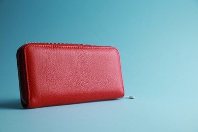 Photo of One stylish leather purse on light blue background. Space for text