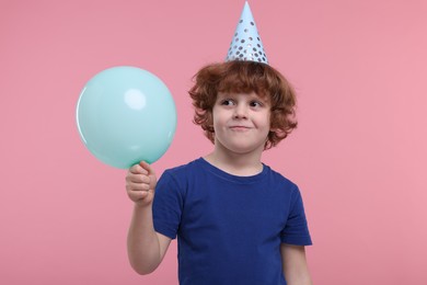 Photo of Cute little boy in party hat with balloon on pink background