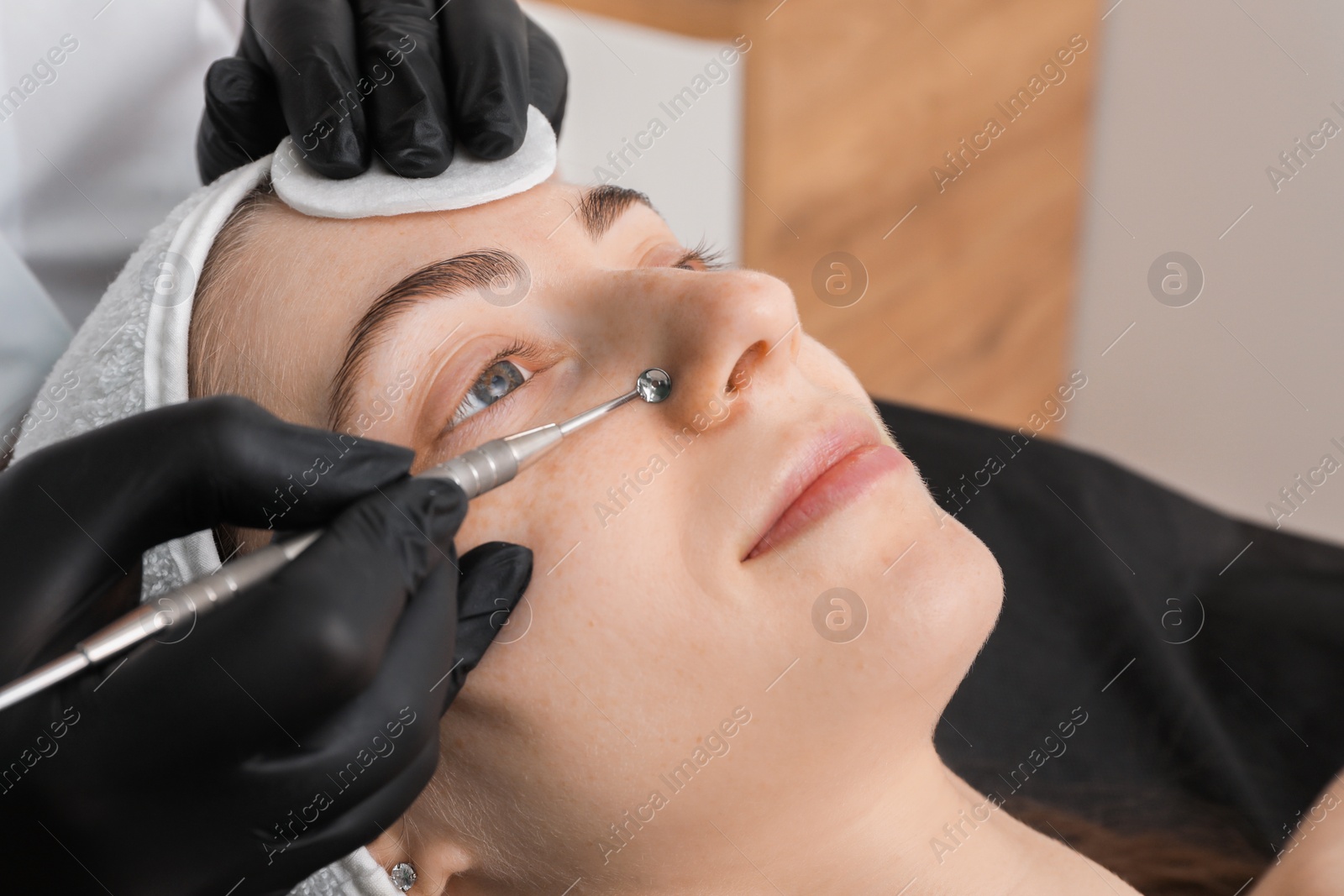 Photo of Cosmetologist using scrubber, closeup. Client having cleansing procedure