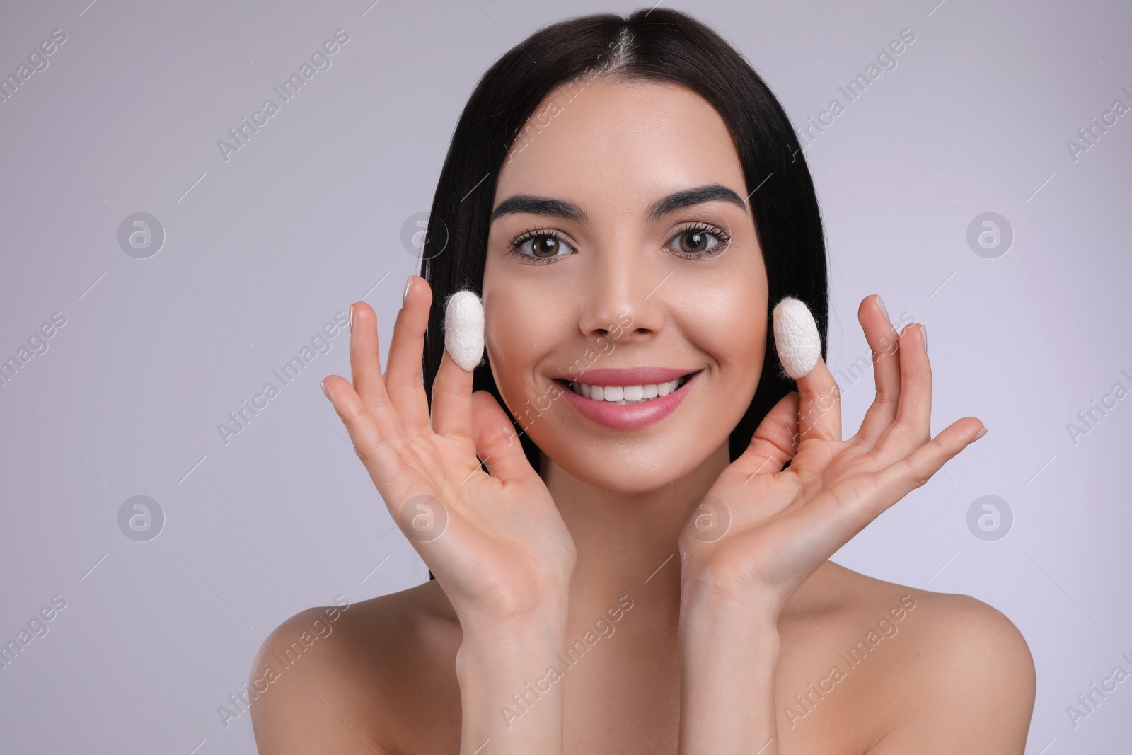 Photo of Woman using silkworm cocoons in skin care routine on light grey background