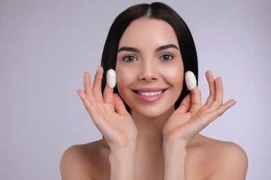 Woman using silkworm cocoons in skin care routine on light grey background