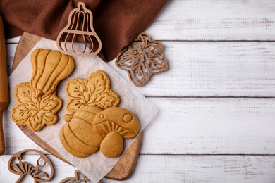 Tasty cookies and cutters on white wooden table, flat lay. Space for text