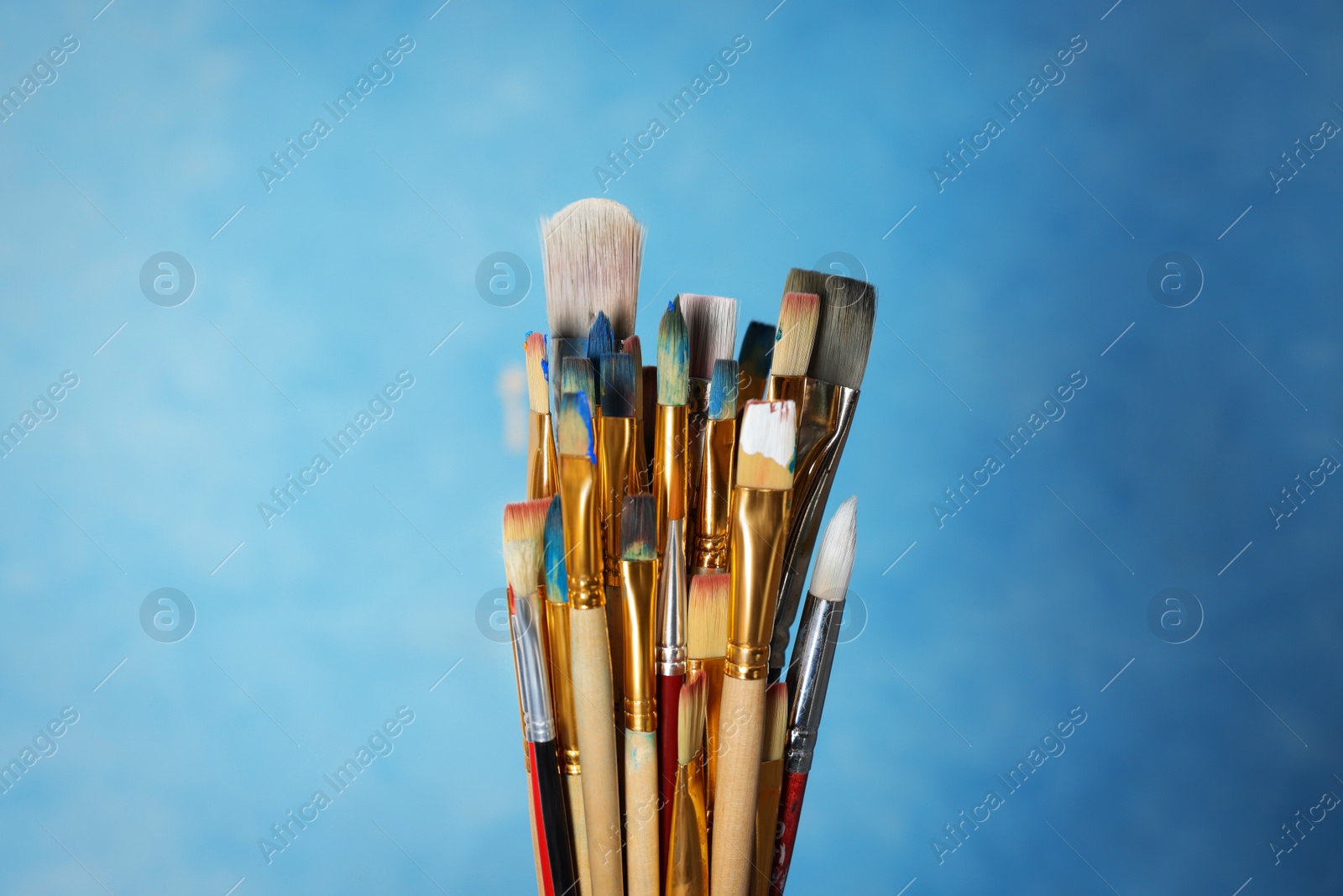 Photo of Many different paintbrushes on light blue background